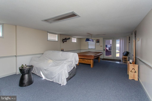 recreation room with a wainscoted wall, carpet flooring, a textured ceiling, and plenty of natural light