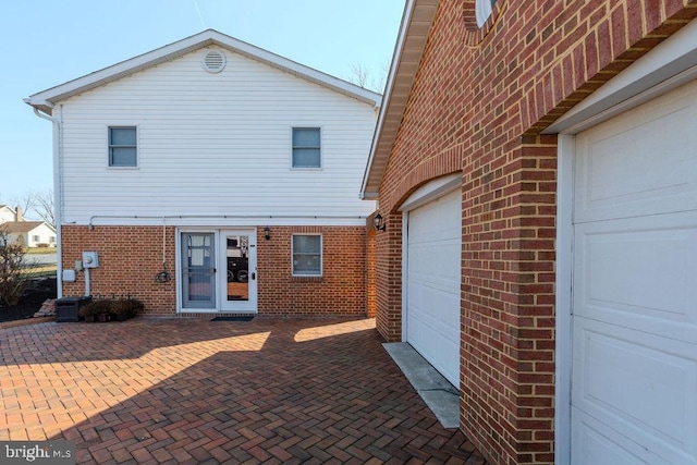 back of property with a garage and brick siding