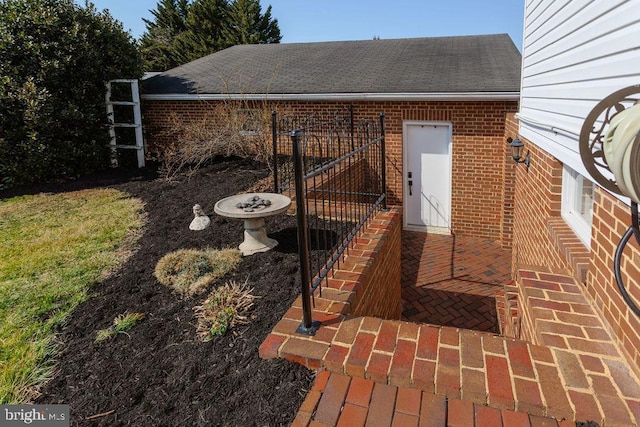 view of property exterior featuring brick siding and roof with shingles