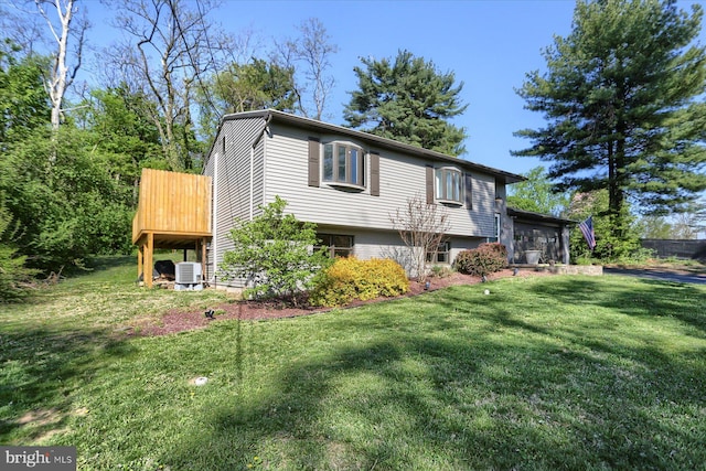 view of side of property featuring a yard and central AC