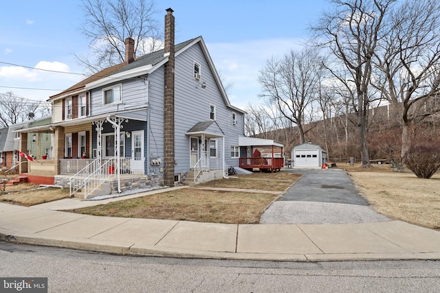 view of front of property featuring an outbuilding, aphalt driveway, a porch, a garage, and a chimney