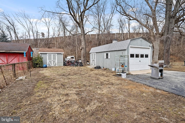 view of yard with an outbuilding, aphalt driveway, a storage shed, and a garage