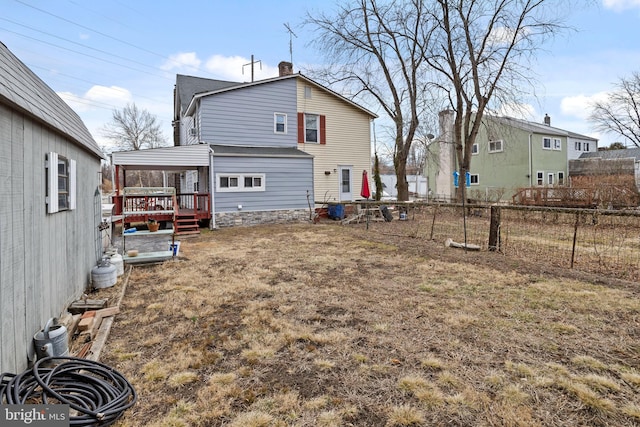 rear view of property featuring a chimney, a wooden deck, and fence