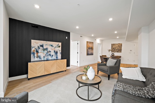 living area with an accent wall, recessed lighting, wood finished floors, and baseboards