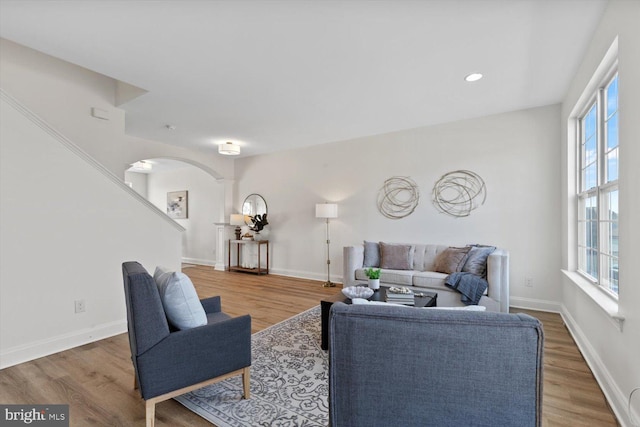 living room with baseboards, arched walkways, wood finished floors, and ornate columns