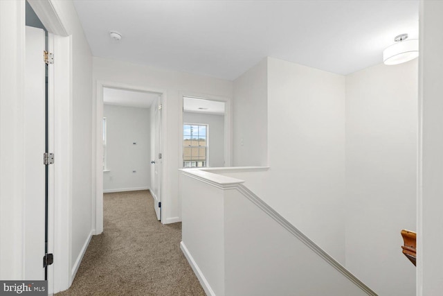 hall featuring carpet, an upstairs landing, and baseboards