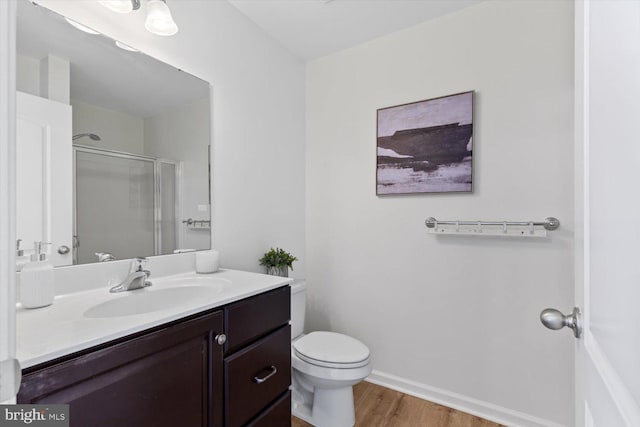 full bathroom with a shower stall, baseboards, toilet, wood finished floors, and vanity