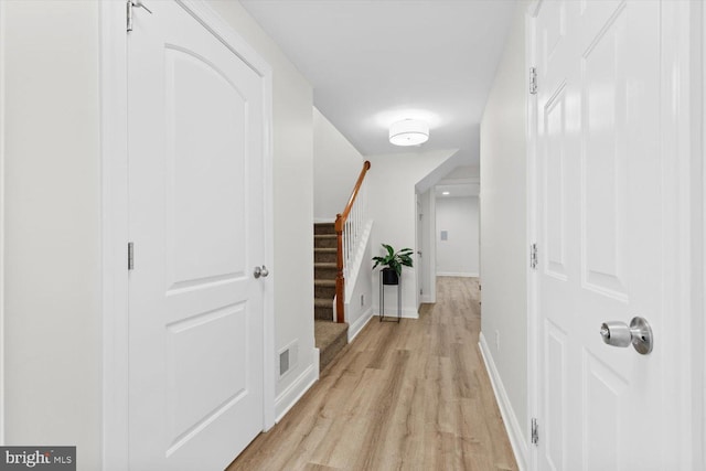 corridor with visible vents, baseboards, light wood-style flooring, and stairs