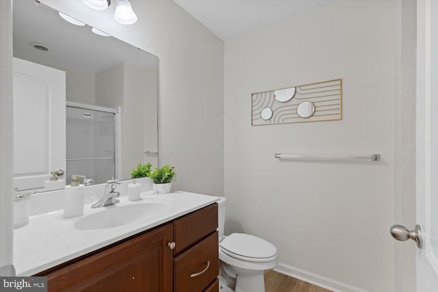 bathroom featuring toilet, vanity, baseboards, and wood finished floors