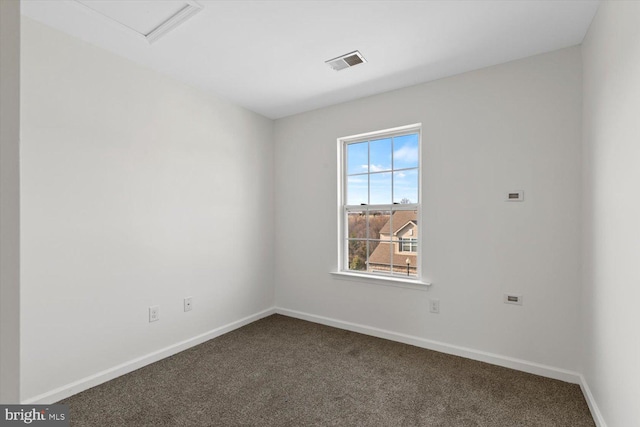 unfurnished room with visible vents, dark carpet, and baseboards