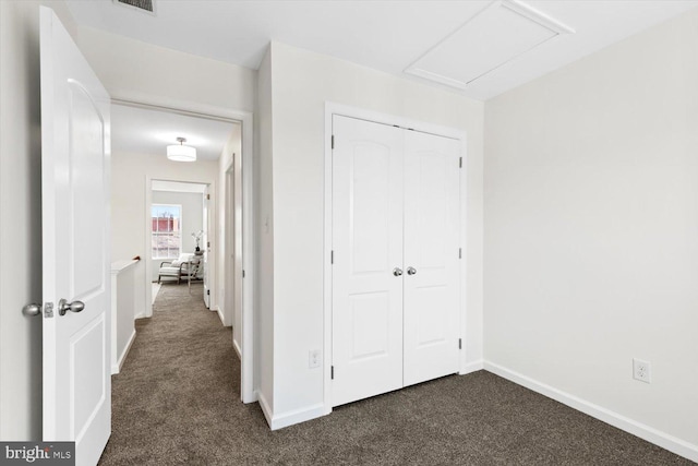 hall with dark colored carpet, visible vents, and baseboards