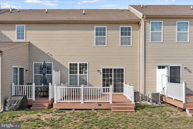 rear view of house featuring a deck, a yard, central AC, and a shingled roof