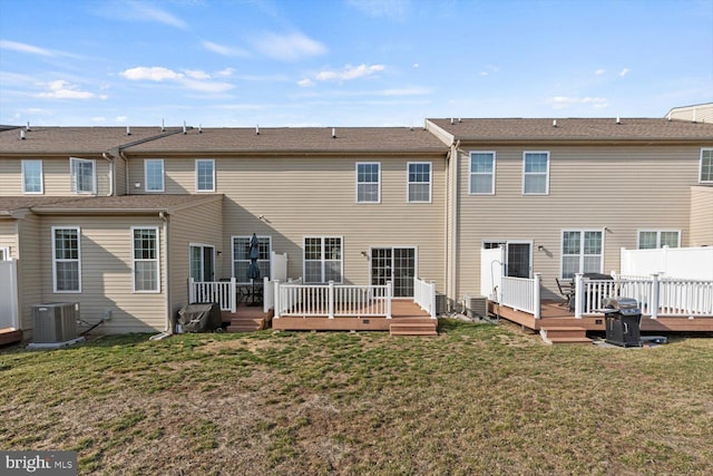 rear view of property featuring central air condition unit, a lawn, and a wooden deck