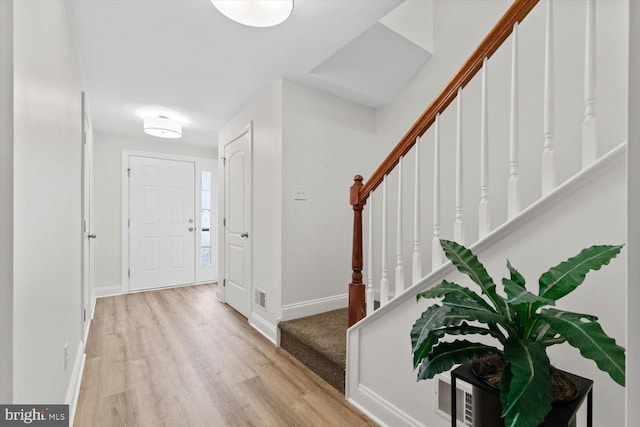 foyer featuring stairway, baseboards, visible vents, and wood finished floors