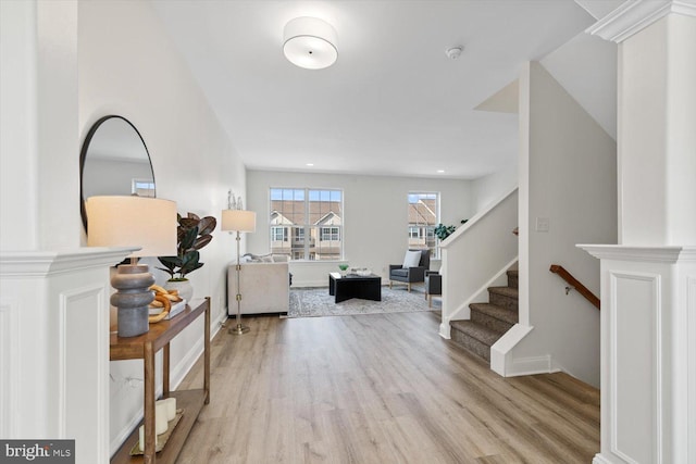 interior space featuring ornate columns, stairway, baseboards, and light wood finished floors