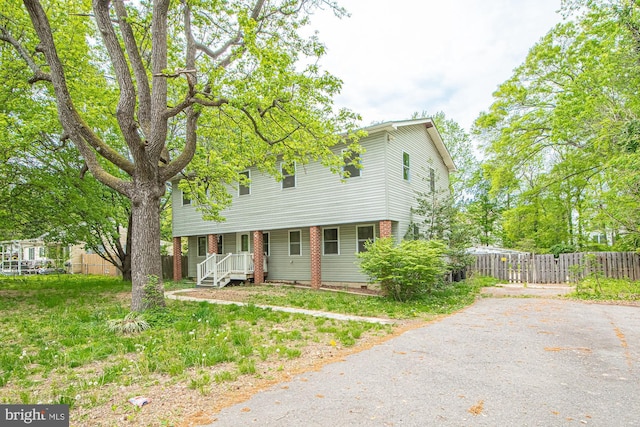 view of front of property with aphalt driveway, covered porch, and fence
