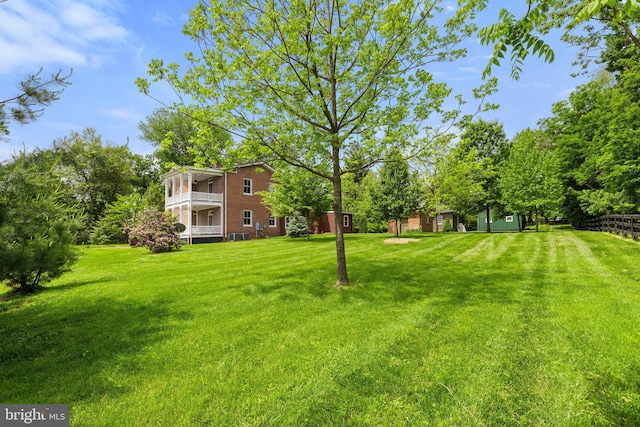 view of grassy yard featuring a balcony