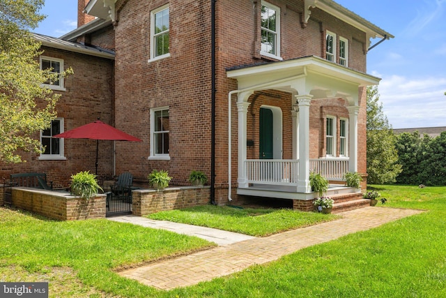 view of front of house with a porch, a front lawn, and brick siding