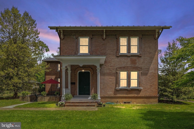 view of front of property featuring brick siding, a yard, and metal roof