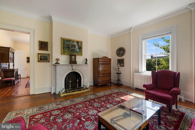 living area featuring radiator heating unit, ornamental molding, hardwood / wood-style flooring, and baseboards