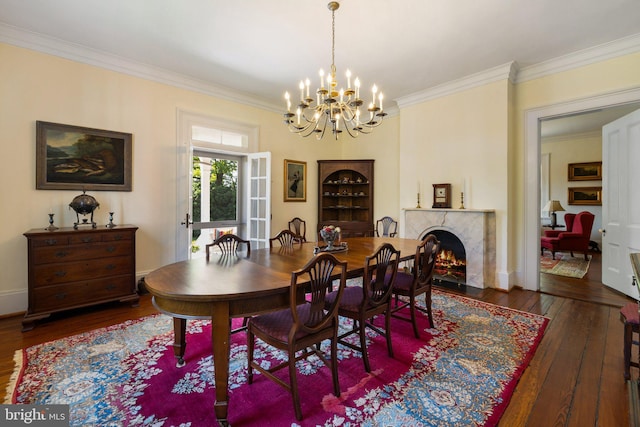 dining space featuring a chandelier, crown molding, hardwood / wood-style floors, and a high end fireplace