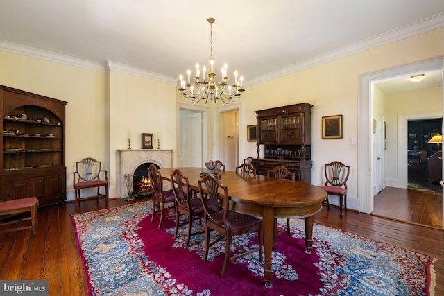 dining room featuring a chandelier, hardwood / wood-style flooring, ornamental molding, baseboards, and a premium fireplace