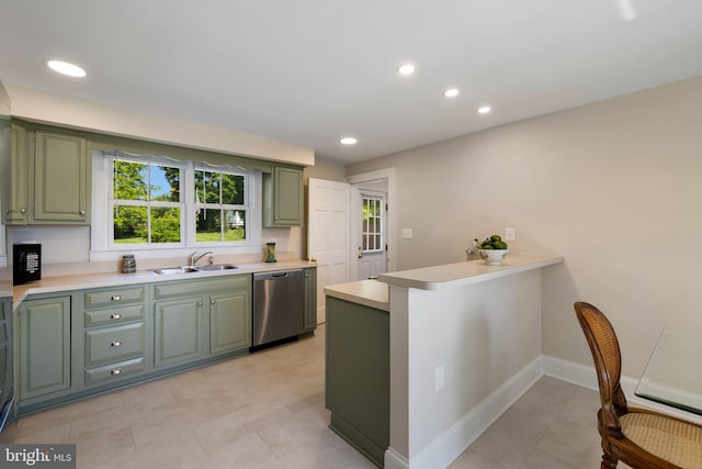 kitchen featuring stainless steel dishwasher, green cabinetry, a sink, light countertops, and a peninsula