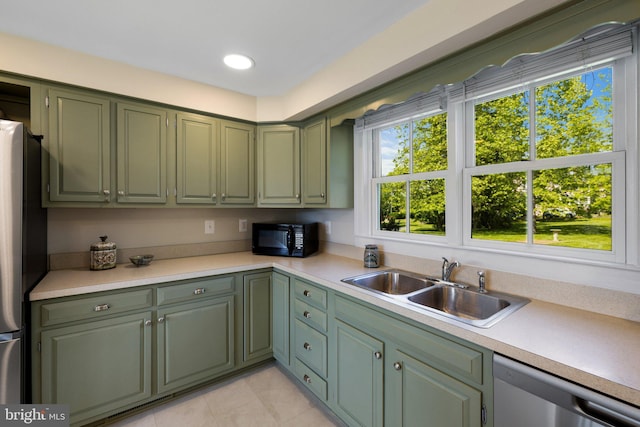 kitchen featuring green cabinetry, appliances with stainless steel finishes, a sink, and light countertops