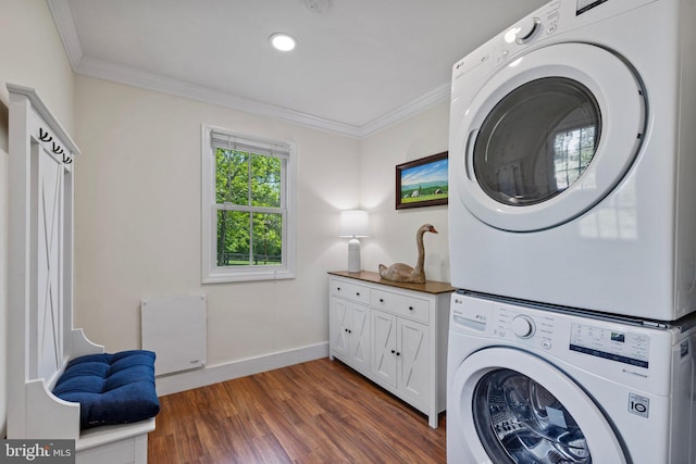 laundry room featuring stacked washer and clothes dryer, cabinet space, ornamental molding, dark wood-style floors, and baseboards