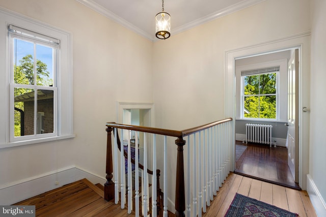 staircase featuring radiator, wood-type flooring, ornamental molding, and baseboards
