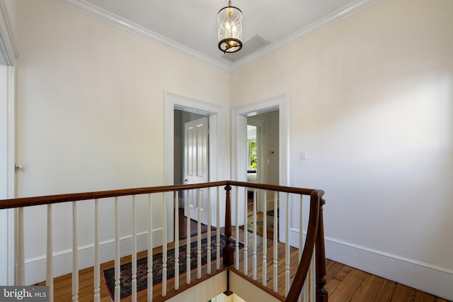 stairs featuring wood finished floors, crown molding, and baseboards