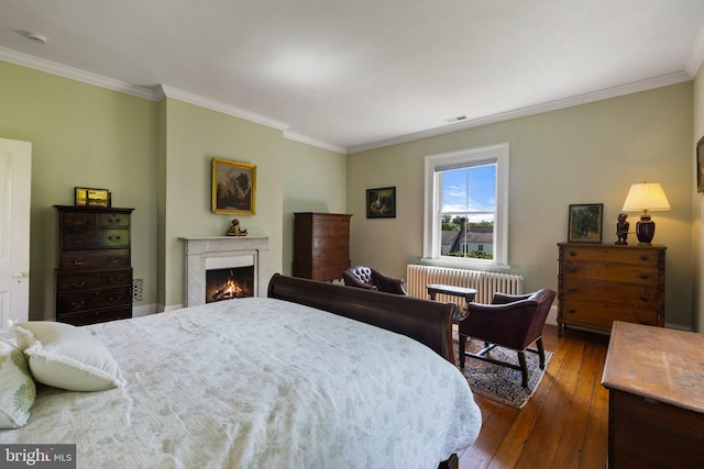 bedroom featuring radiator, crown molding, dark wood-style floors, and a lit fireplace