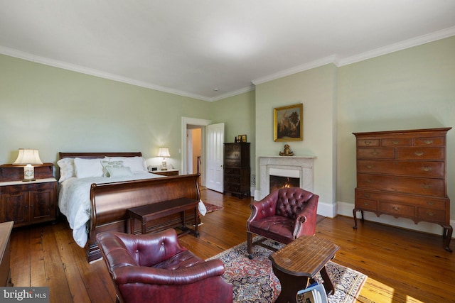 bedroom featuring hardwood / wood-style flooring, ornamental molding, a lit fireplace, and baseboards