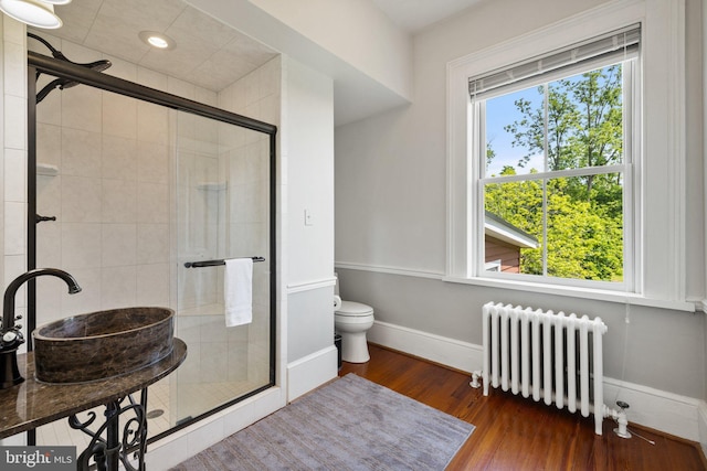 full bath featuring radiator, a shower stall, toilet, wood finished floors, and recessed lighting