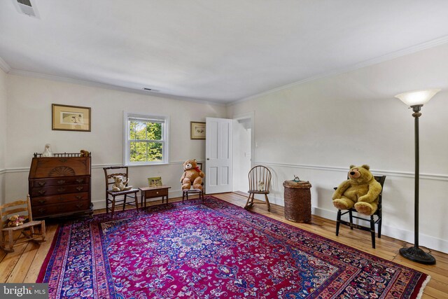 living area featuring wood-type flooring and ornamental molding