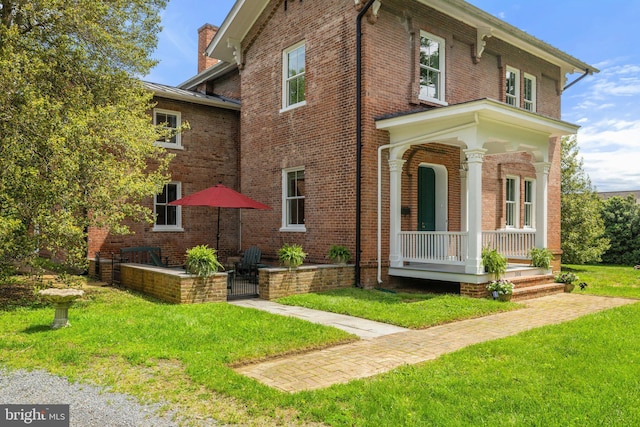 view of front of house featuring a porch, a front yard, and brick siding