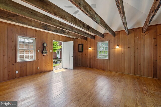 unfurnished living room featuring beamed ceiling, hardwood / wood-style floors, and wooden walls