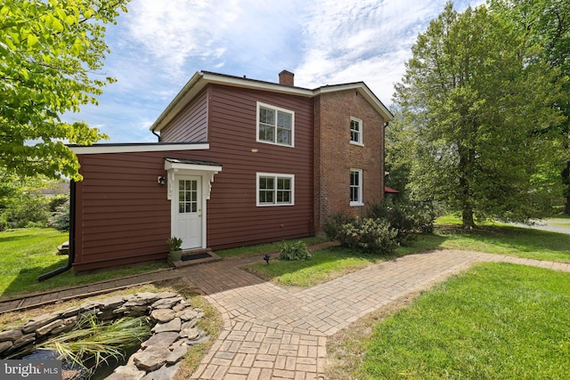 rear view of property with a chimney and a yard