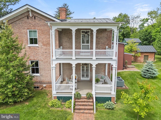 view of front of home with a balcony, a chimney, brick siding, covered porch, and a standing seam roof