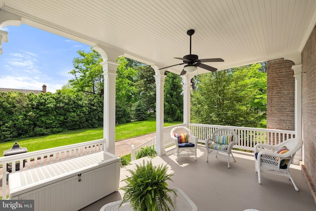view of patio featuring covered porch, ceiling fan, and view of scattered trees