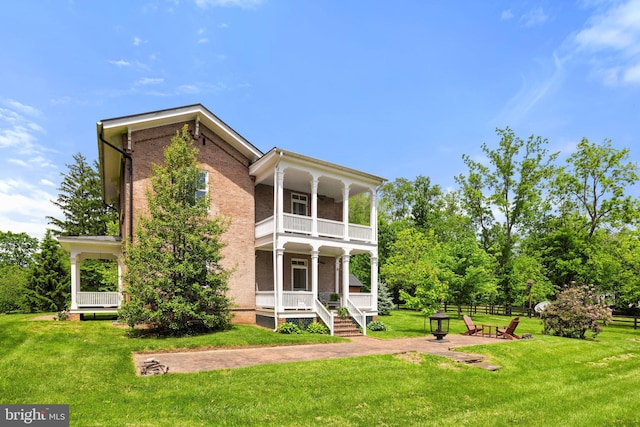 rear view of property with a balcony, a porch, and brick siding
