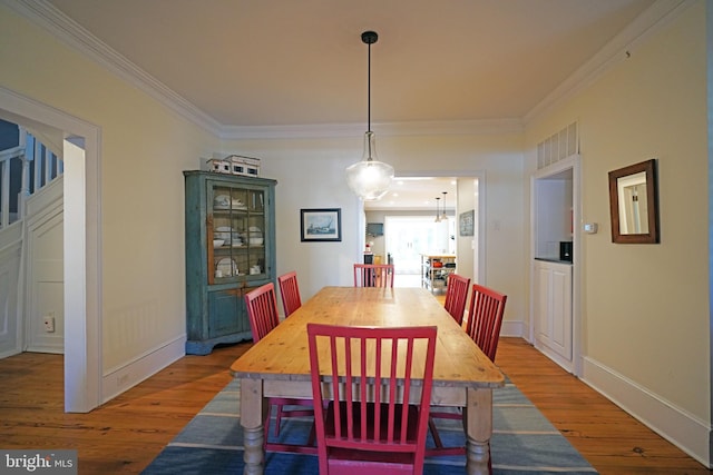 dining space featuring baseboards, ornamental molding, and wood finished floors