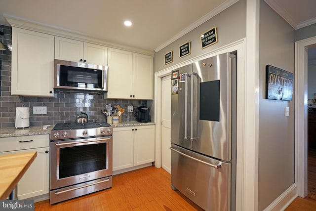 kitchen featuring backsplash, crown molding, light wood-type flooring, stainless steel appliances, and white cabinetry