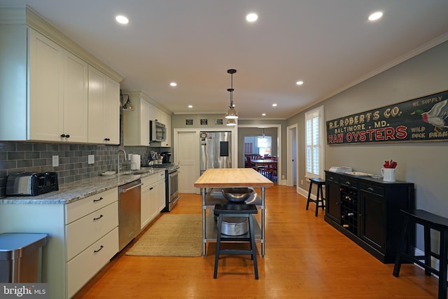 kitchen with crown molding, appliances with stainless steel finishes, butcher block counters, and a sink