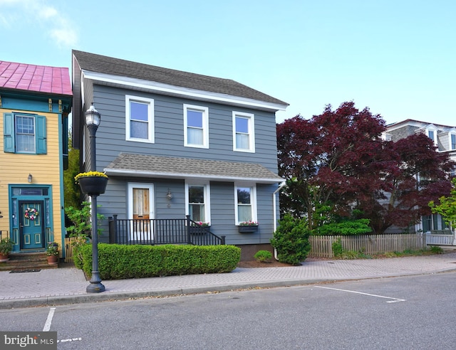 traditional-style home featuring fence, uncovered parking, and roof with shingles