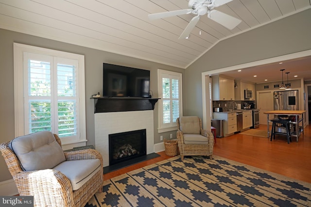 living area featuring ceiling fan, plenty of natural light, light wood-style flooring, and lofted ceiling