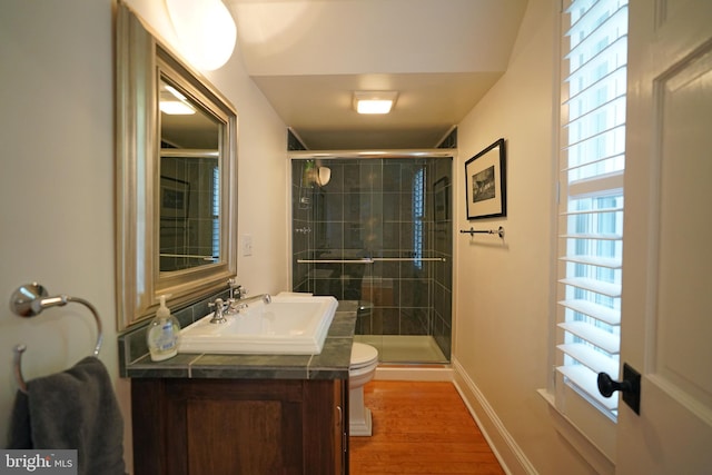 bathroom with vanity, toilet, baseboards, wood finished floors, and a stall shower