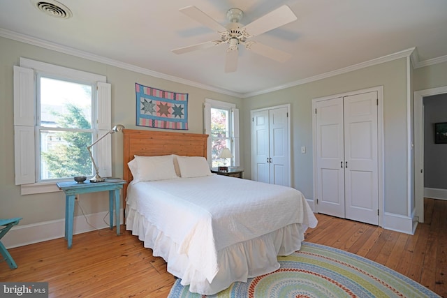 bedroom featuring visible vents, crown molding, two closets, baseboards, and light wood-type flooring