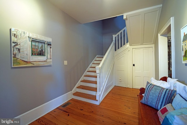 staircase featuring baseboards, hardwood / wood-style floors, and visible vents