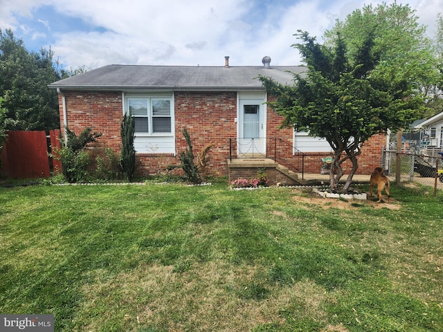 view of front of house featuring brick siding, fence, and a front lawn